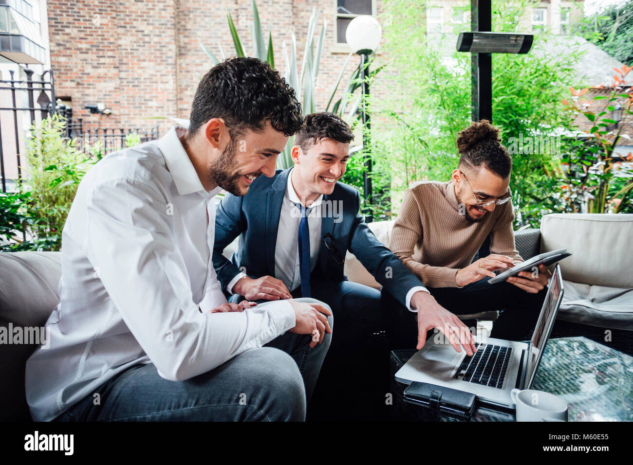 Los empresarios están trabajando juntos sobre la tecnología inalámbrica en una reunión de negocios que están teniendo lugar en un bar Patio. Foto de stock