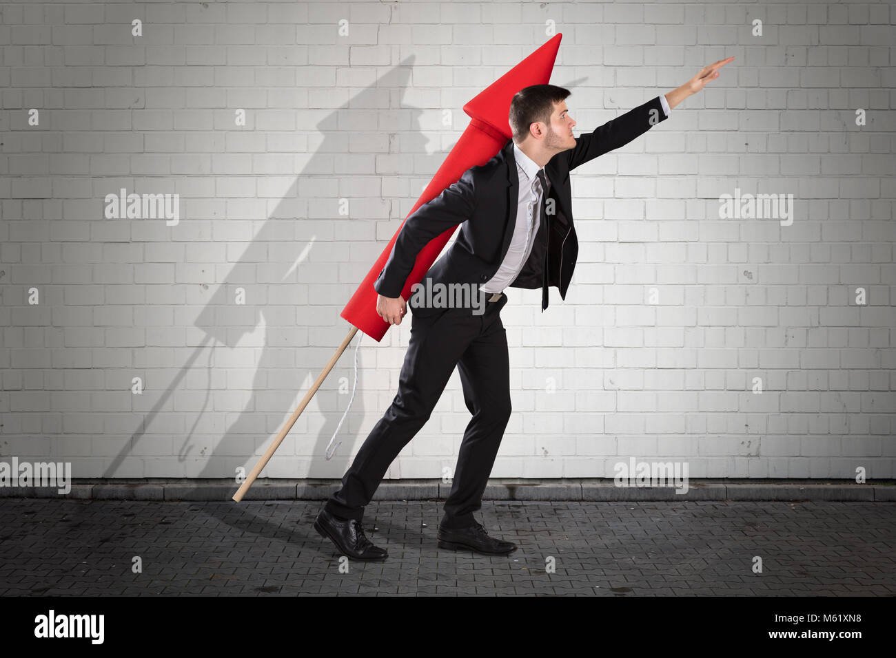 Joven Empresario volando con la Red Rocket Contra la pared de ladrillo Foto de stock