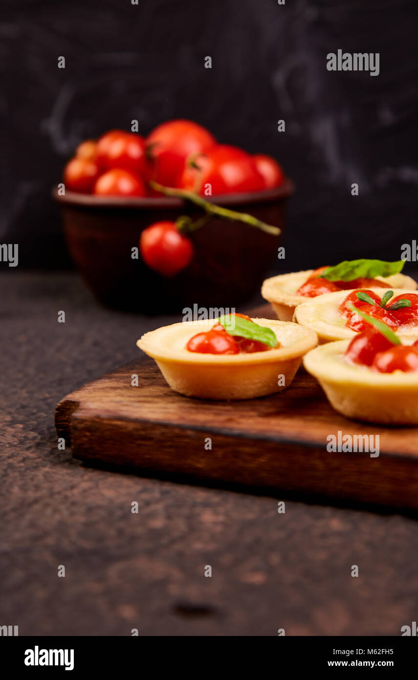 Mini tartas con tomates cherry con queso mozzarella sobre la plancha de  madera Fotografía de stock - Alamy