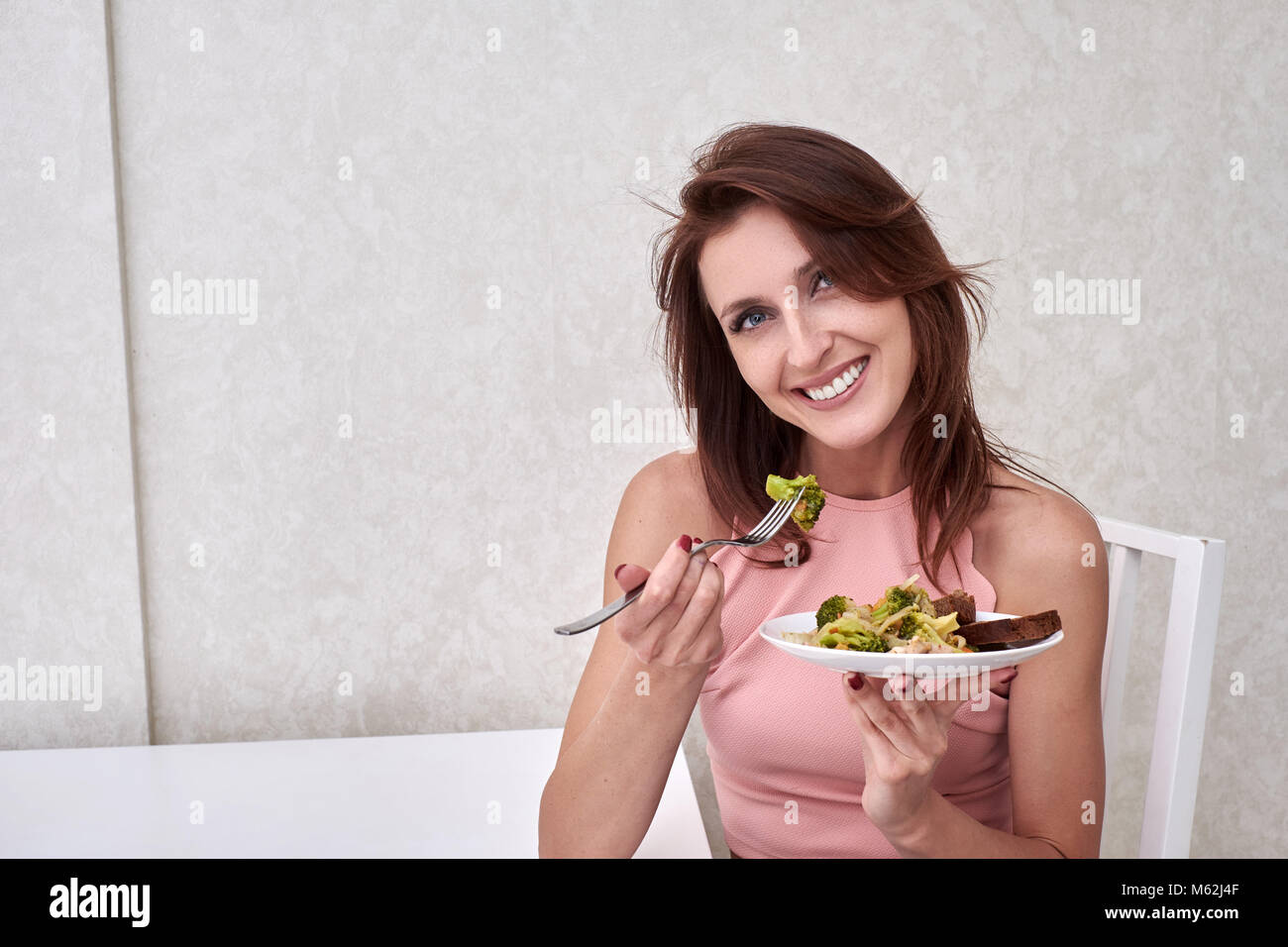 La mujer está en dieta feliz tiempo mirando el brócoli en la horquilla. Concepto comida sana Foto de stock