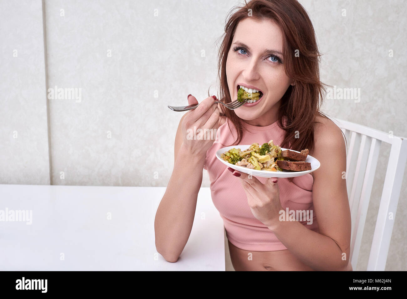 La mujer está en dieta feliz tiempo mirando el brócoli en la horquilla. Concepto comida sana Foto de stock