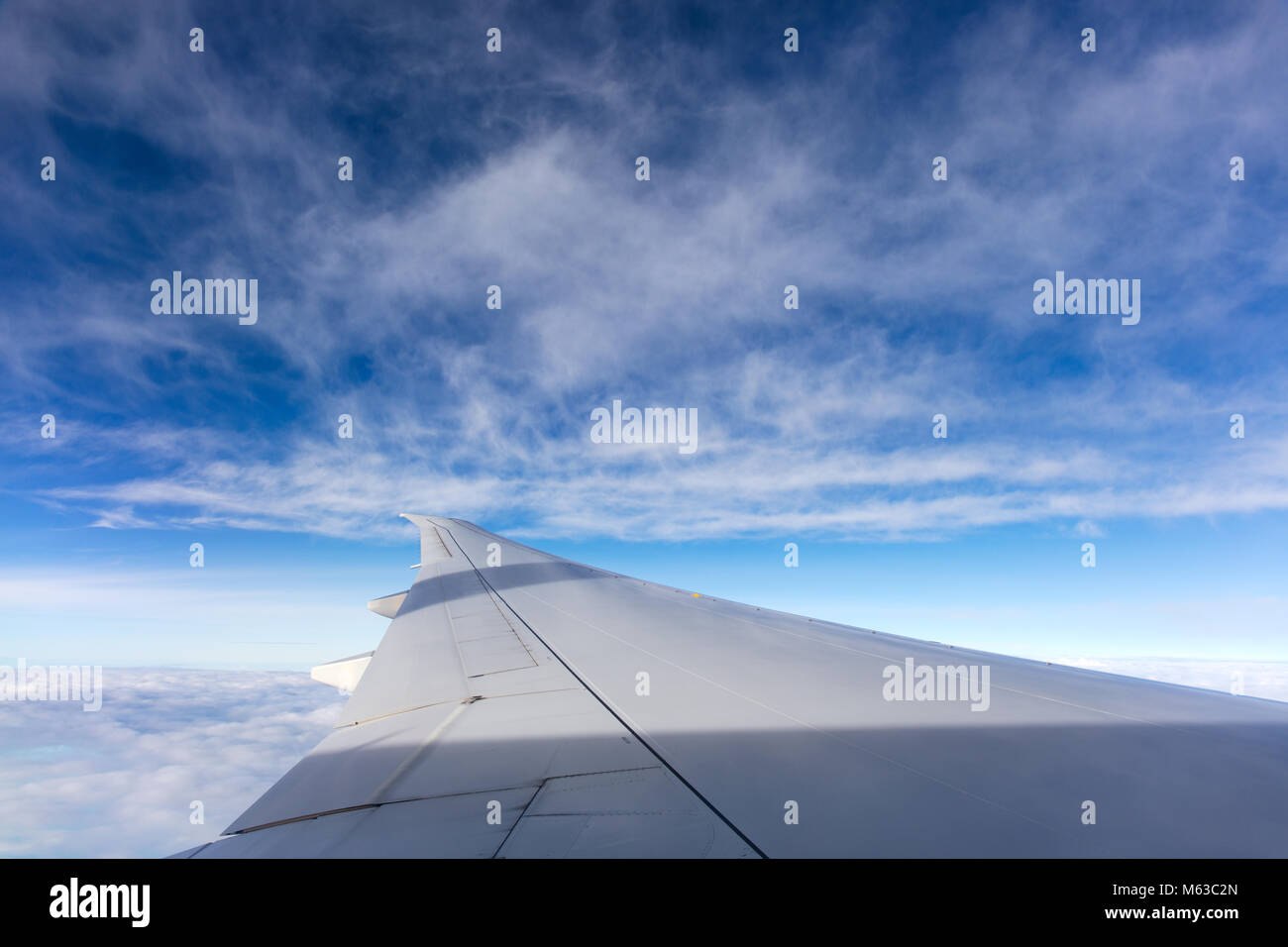 El ala de un Boeing 777 con un nublado cielo azul en el fondo. Foto de stock