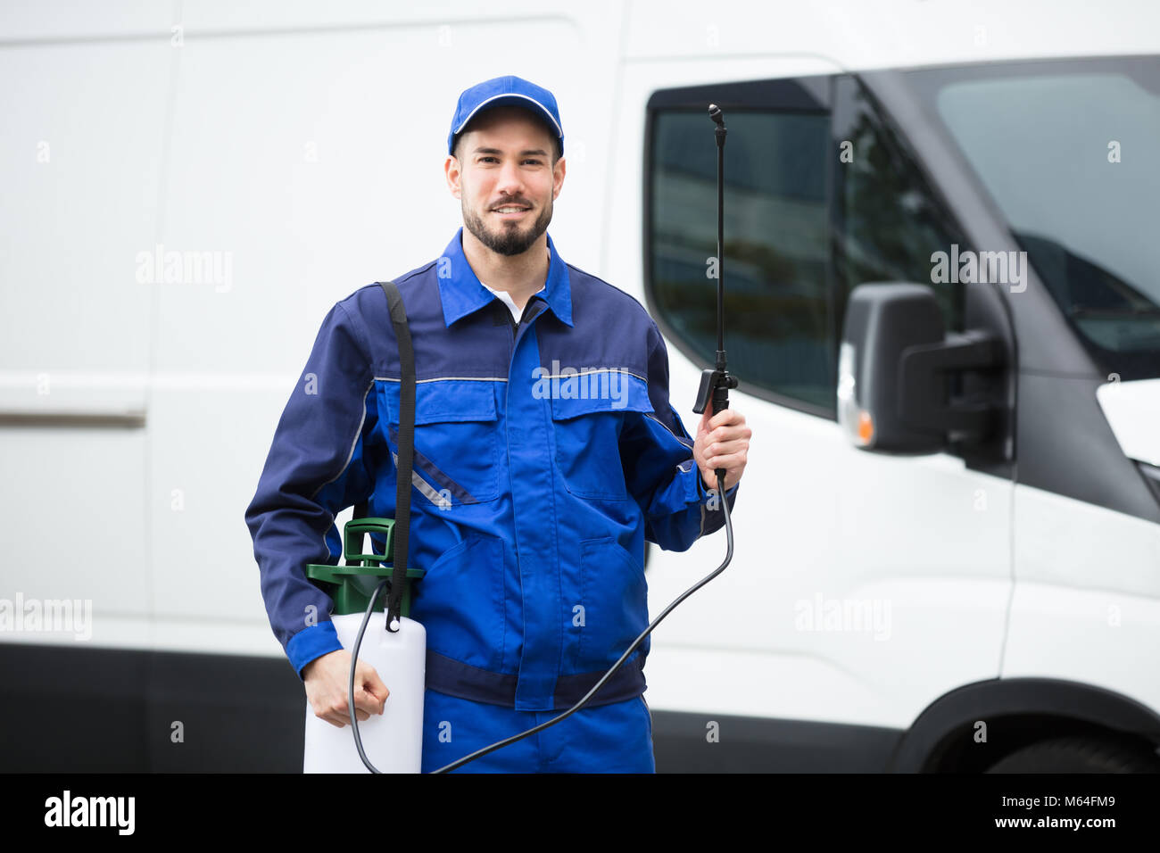 Retrato de un sonriente macho Trabajador de Control de Plagas de pie en la parte delantera del vehículo Foto de stock