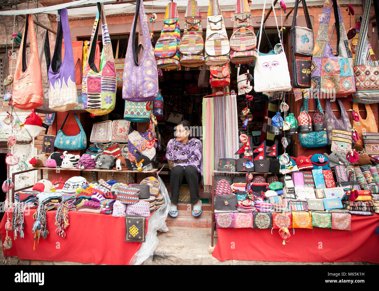 PATAN - 20 DE MAYO : mujer no identificada sentada en las escaleras delante de su tienda en Patan, Nepal el 20 de mayo de 2013. Patan es conocida por sus ricos cultu Foto de stock