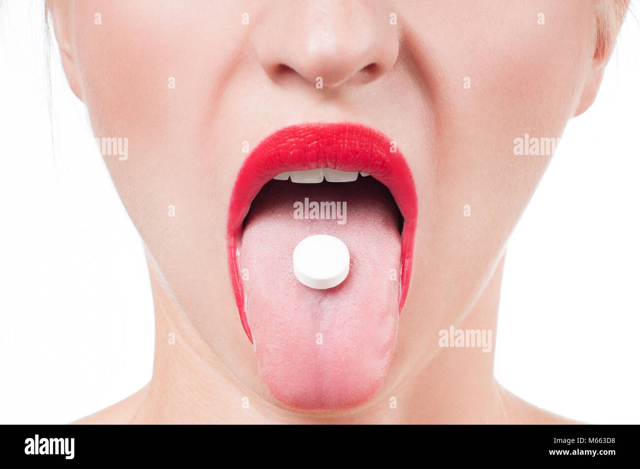 Mantiene la boca abierta medicina píldora de la lanza. Mujer con labios rojos tomando la medicina. Foto de stock