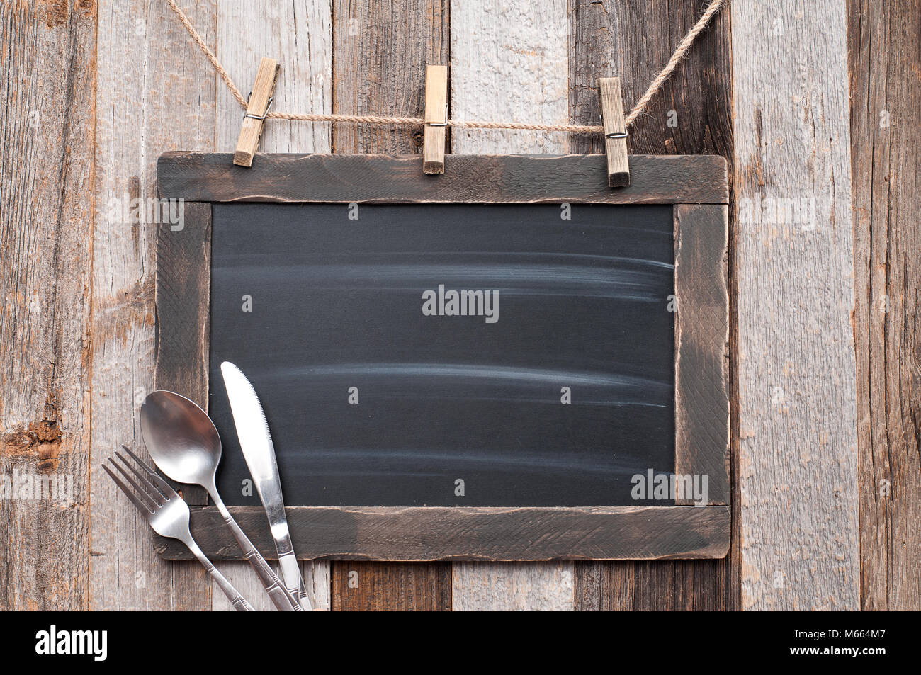 Pizarra de menú con un cuchillo, una cuchara de madera y la horquilla en el  fondo. Vintage chalk board pizarra Fotografía de stock - Alamy