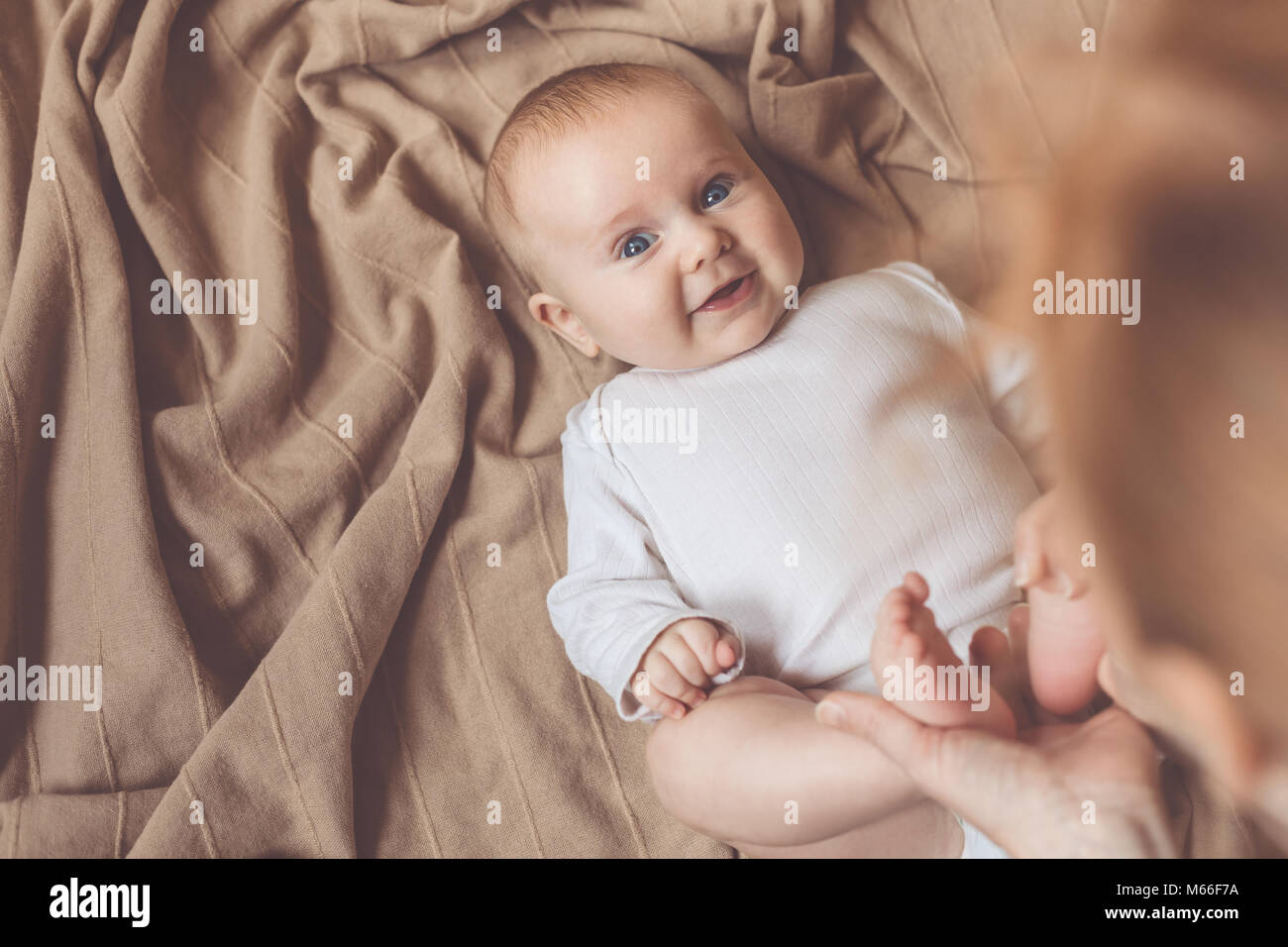 Los vestidos de mamá al bebé en la cama en el día Fotografía de stock -  Alamy
