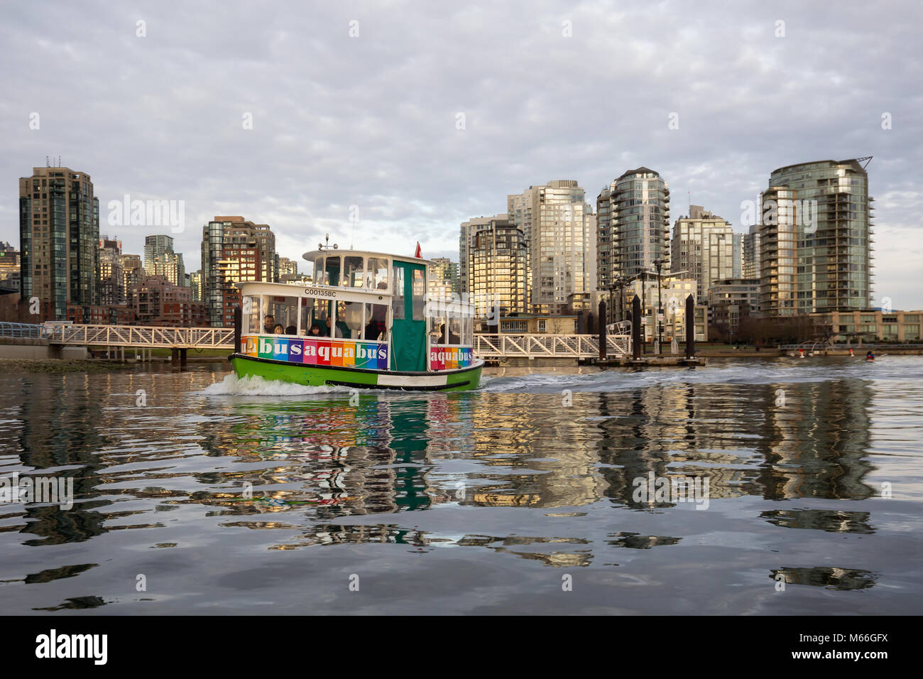 El centro de Vancouver, British Columbia, Canadá - 28 de enero de 2017 - Un pequeño taxi barco monta en False Creek durante un vibrante atardecer de invierno. Foto de stock