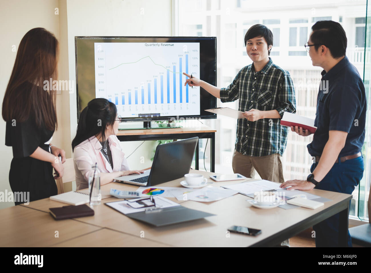 La empresaria asiática y debatir ideas con jóvenes hombre freelance en la sala de reuniones. Empresa co-operar con externalizar el concepto de trabajador. Foto de stock