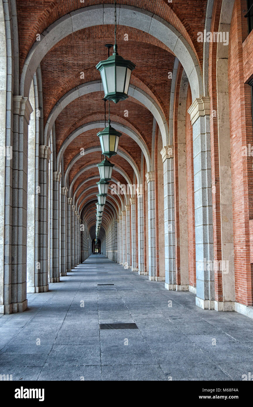 Galería porticada con arcos de piedra y techos de ladrillo farolas colgado en un edificio de Nuevos Ministerios en Madrid. España Foto de stock