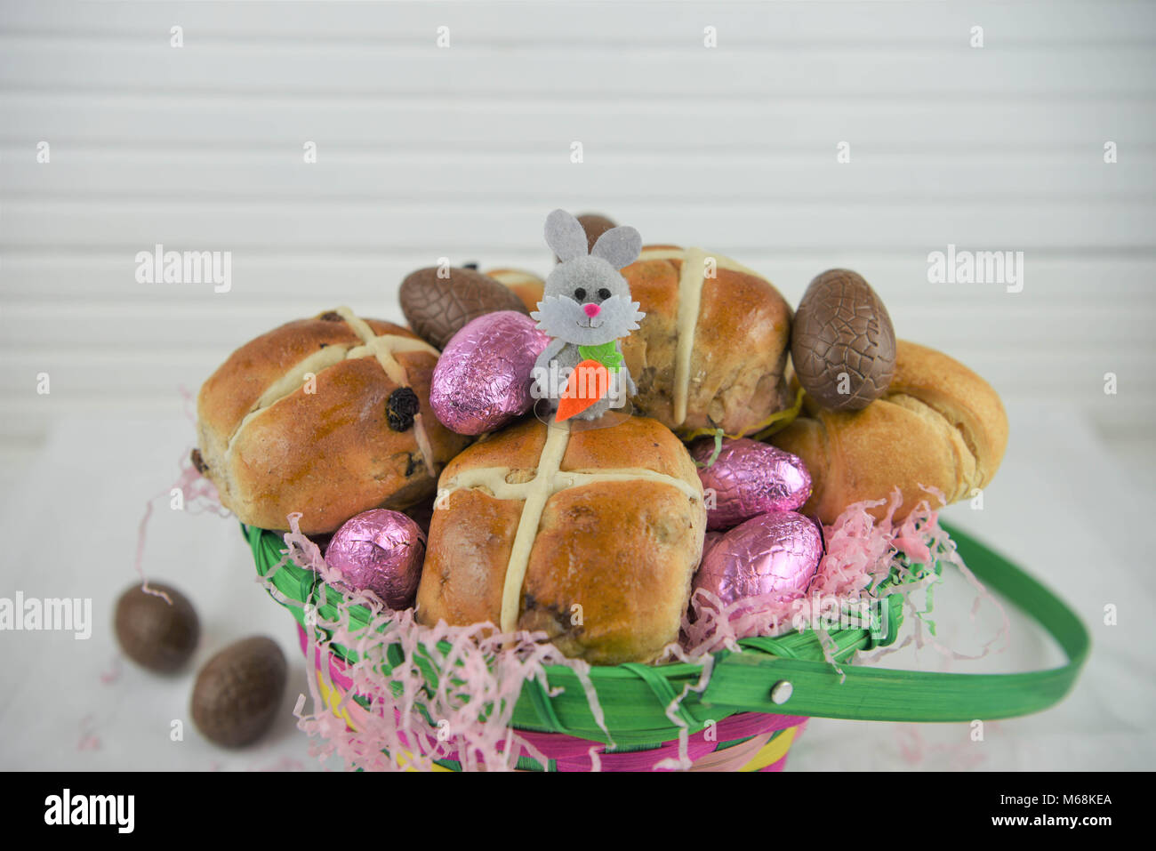 Comida de Pascua en una cesta con Hot Cross Buns y chocolate y huevos de Pascua conejito lindo decoración Foto de stock
