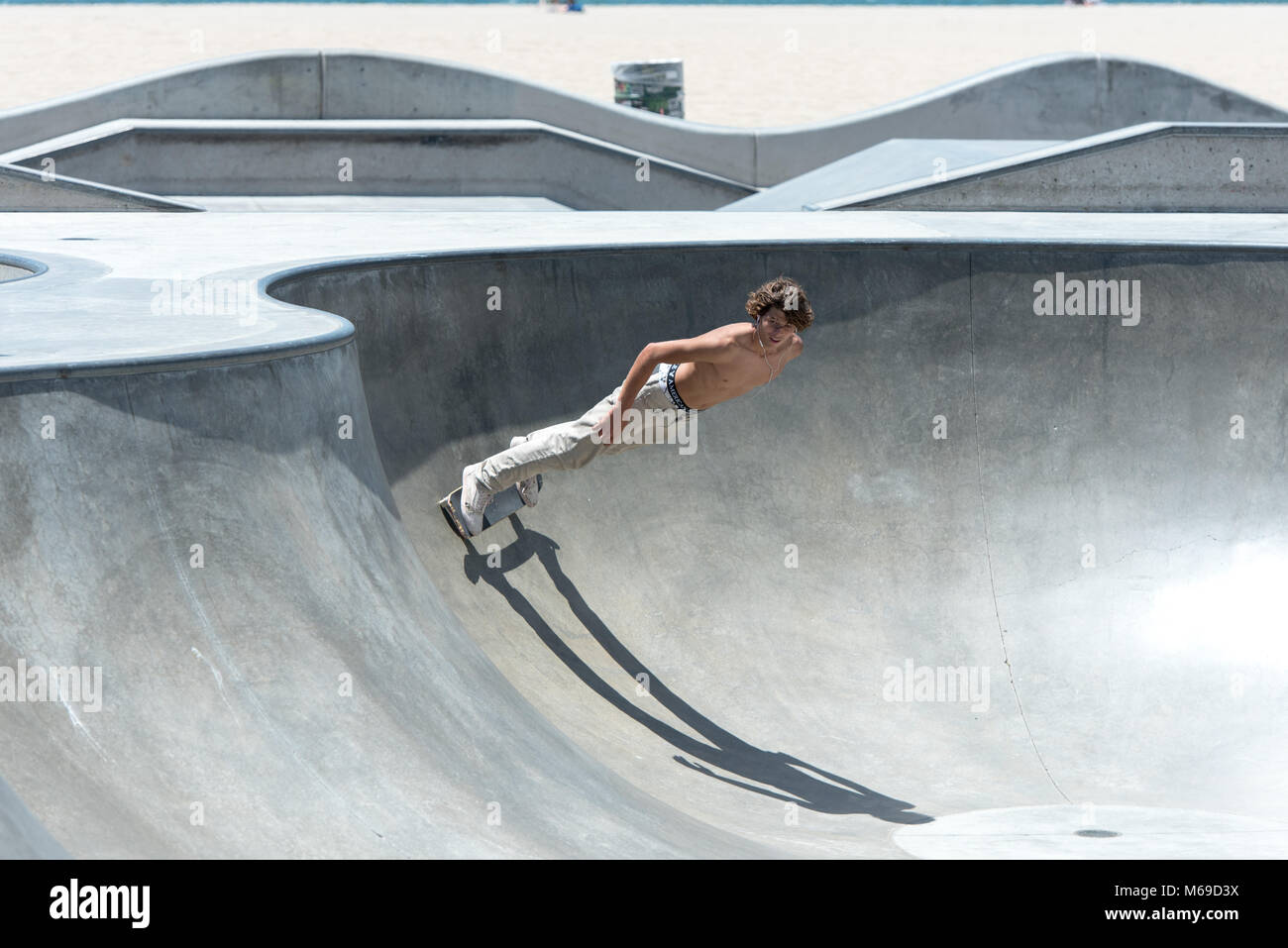 Joven skater en el skatepark en la mundialmente famosa playa de Venice Boardwalk, una de las atracciones más populares de California. Foto de stock