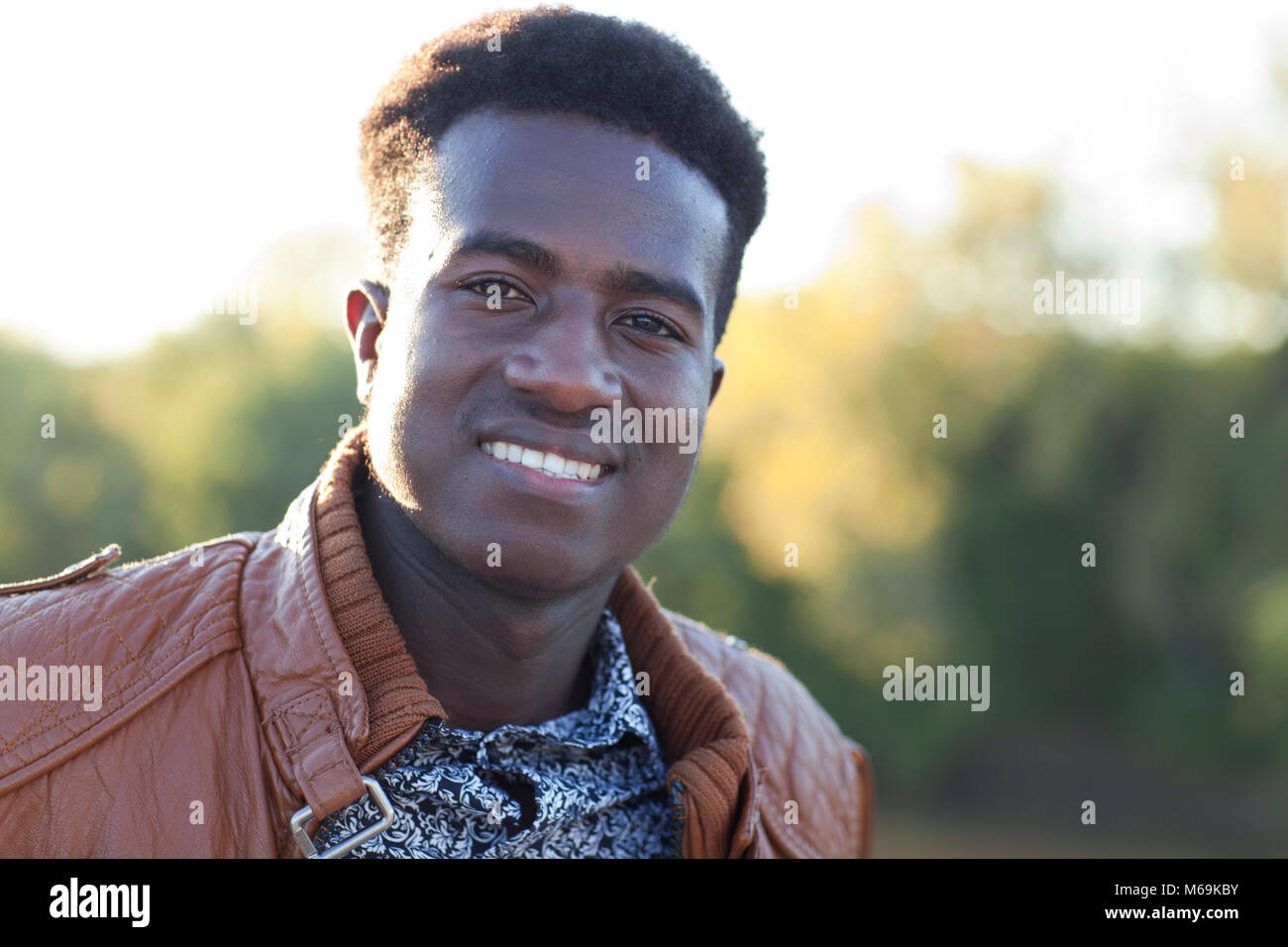Apuesto joven negro sonriendo delante del efecto de desenfoque de fondo Foto de stock