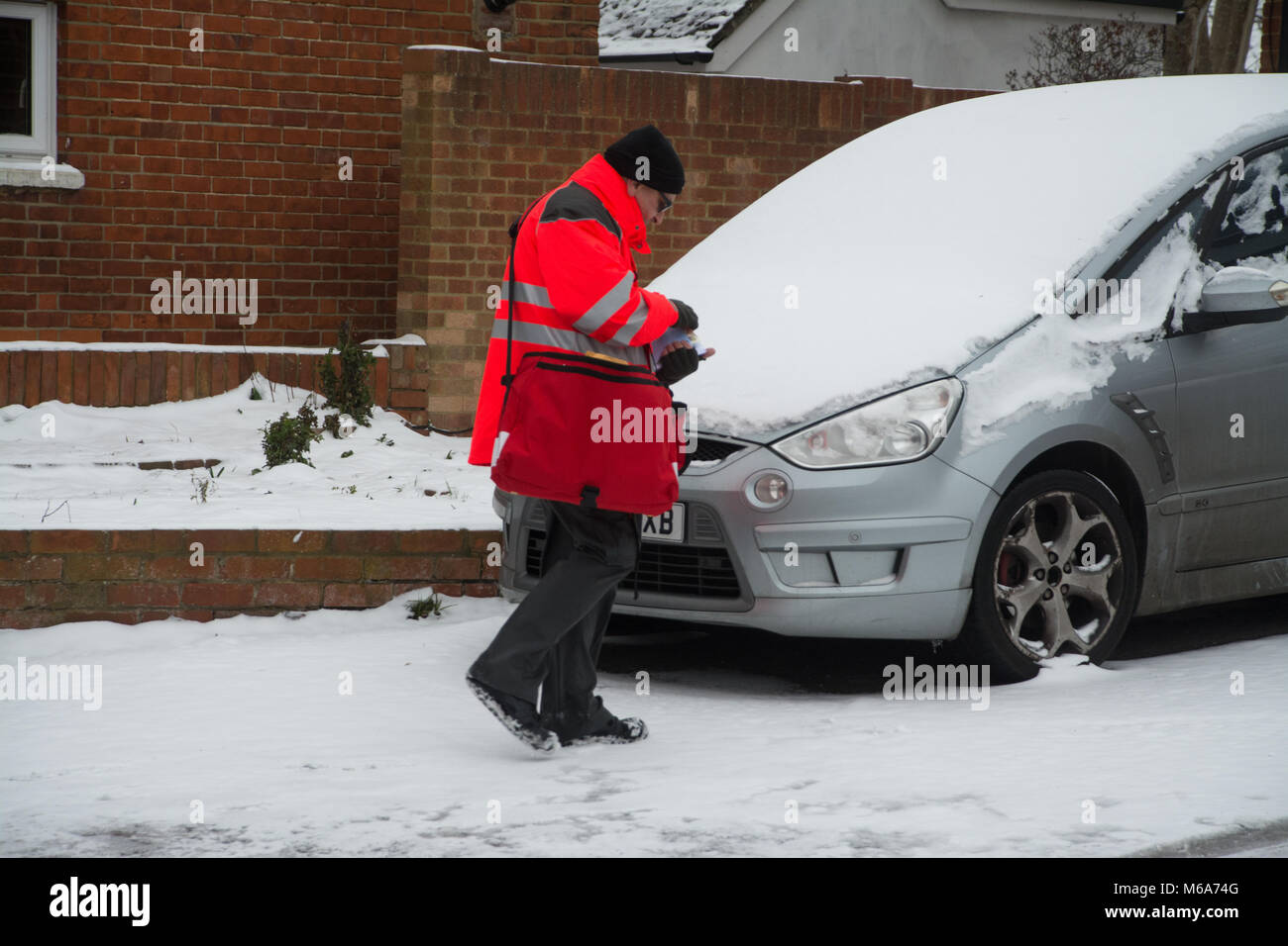 Farnborough, Hampshire, Reino Unido. El 2 de marzo de 2018. Una fría mañana gris con mucha nieve todavía acostado en el suelo. Un cartero desafiaron la nieve. Foto de stock