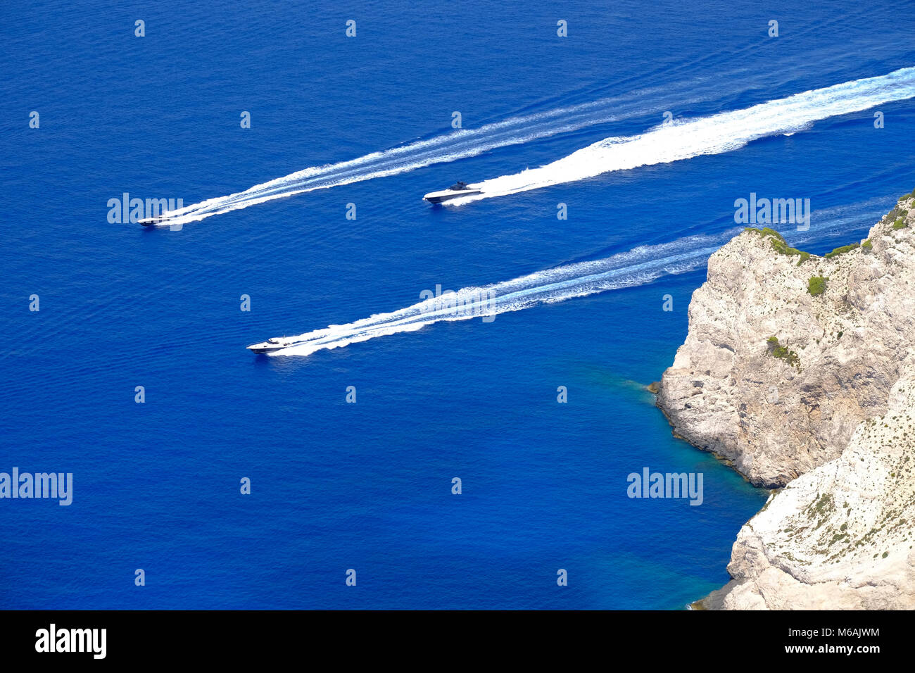 Los barcos corriendo a alta velocidad en aguas claras cerca del acantilado de la isla de Zakynthos, Grecia Foto de stock