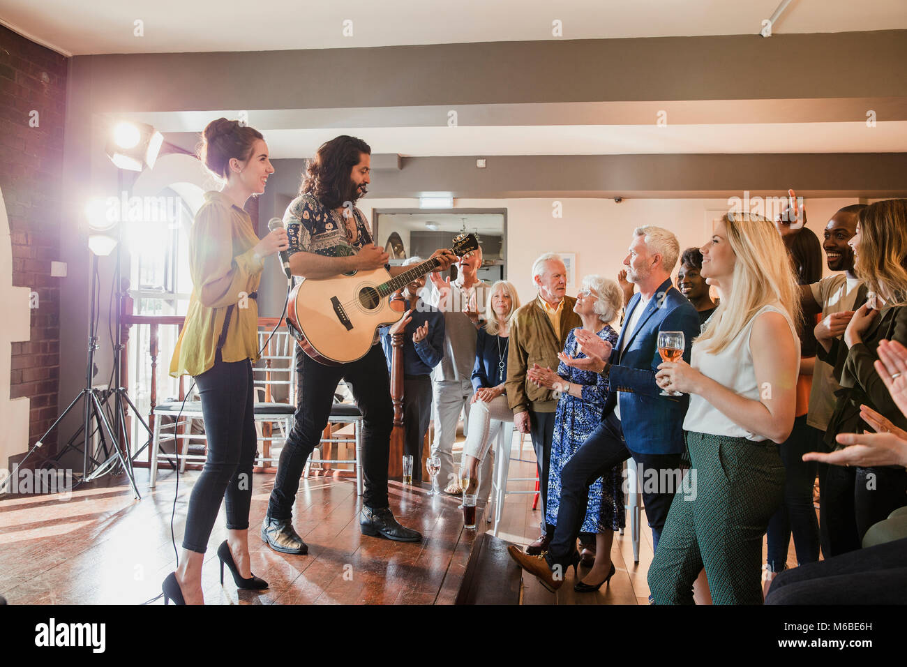 Los invitados a la boda están disfrutando algunos entretenimiento acústicos. Hay un hombre tocando la guitarra y una mujer cantando y todo el mundo está bailando junto. Foto de stock