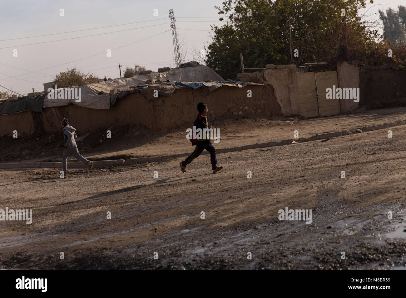 Mosul, Iraq. 8 Diciembre 2016 - 2 chicos ejecutar para cubrir en las calles de Mosul durante una coalición campaña para librar de Daesh de Mosul. - Â© Ty Faruki Foto de stock