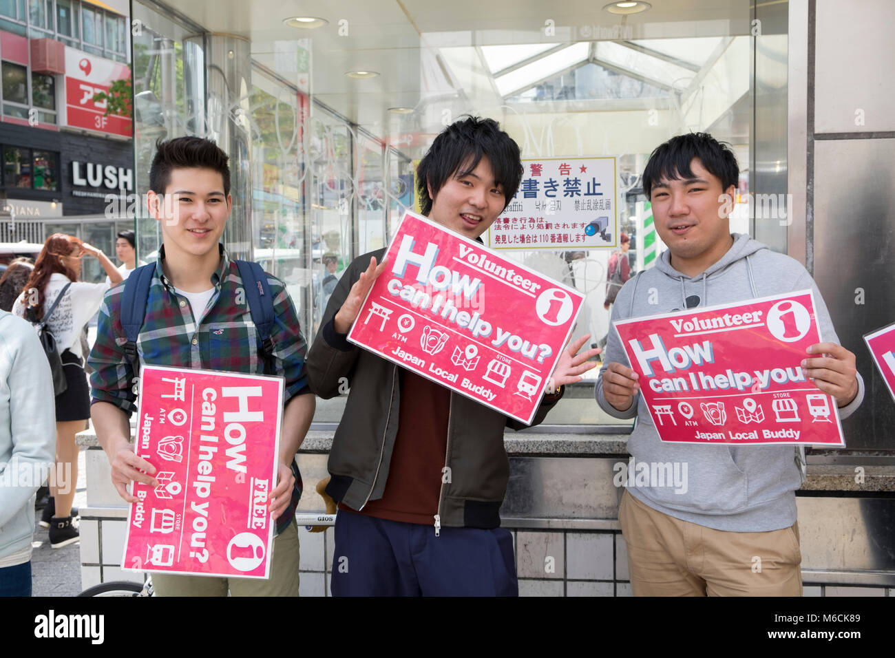 Los jóvenes estudiantes voluntarios dispuestos a ayudar a los turistas en el cruce Shibuya, Tokio, Japón Foto de stock