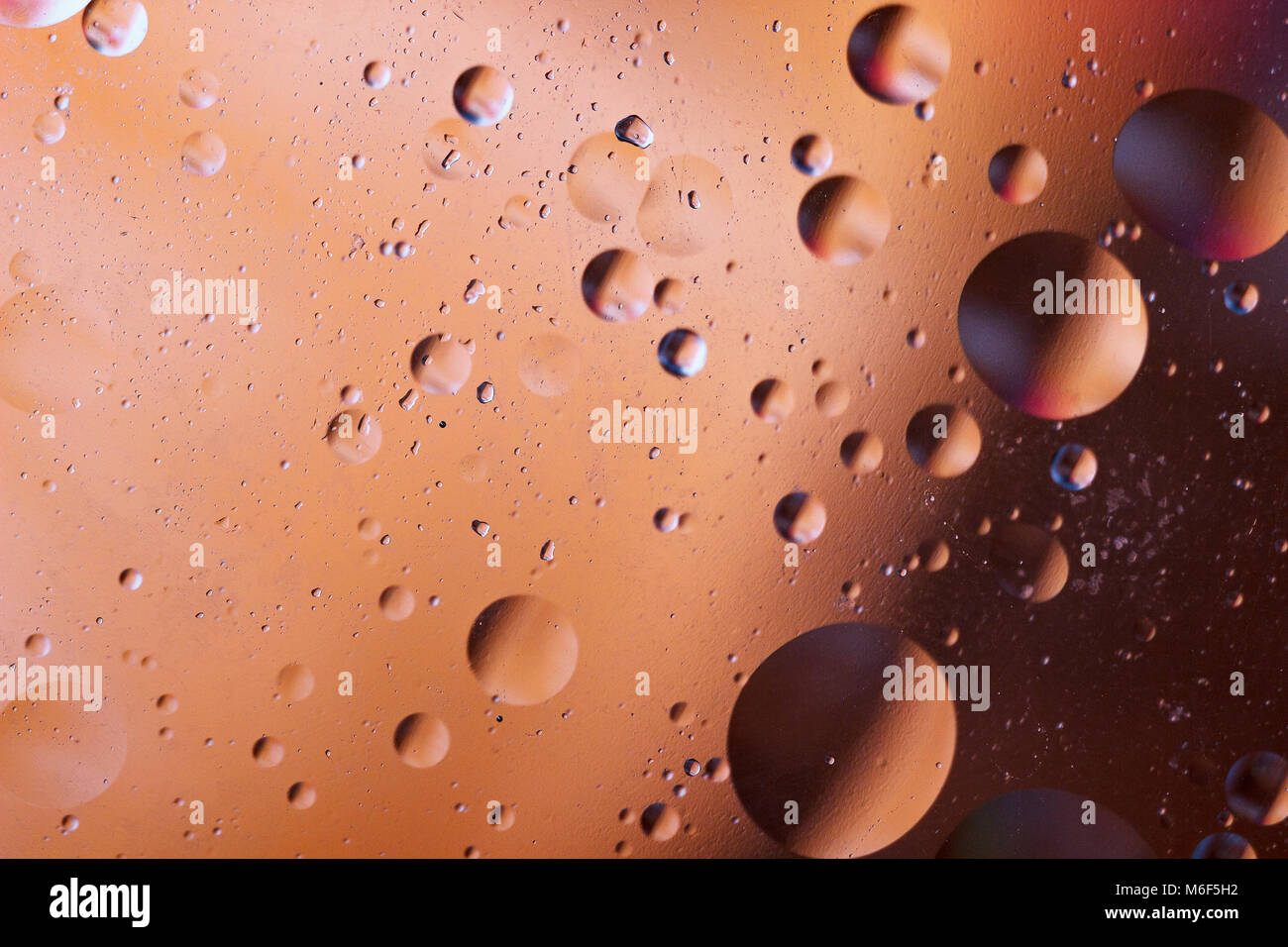 Burbujas de aceite en un medio acuoso en la frontera, con una superficie de cristal. Protector de pantalla de abstractos. Foto de stock