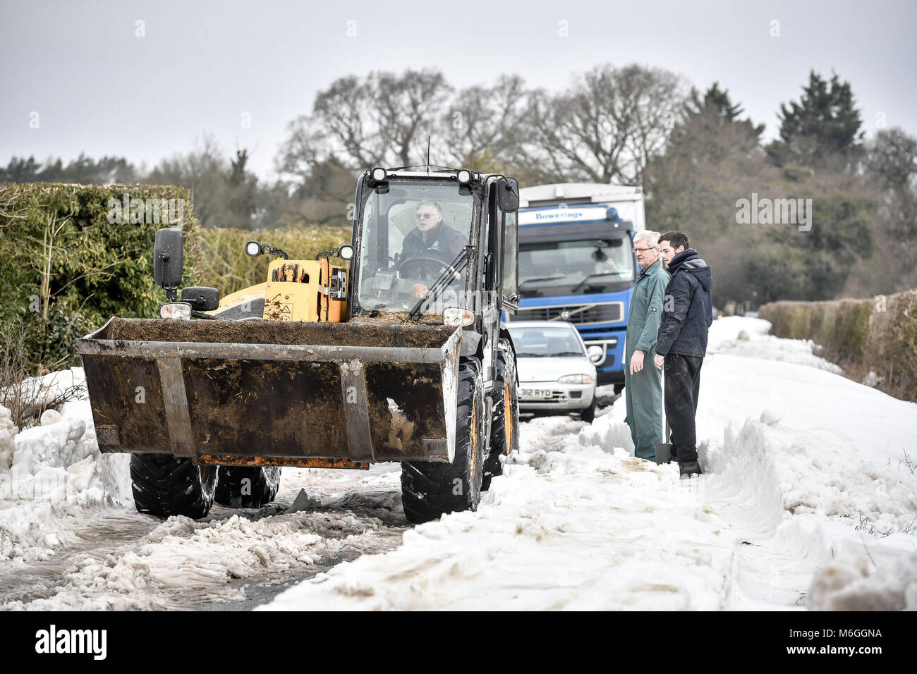 Una JCB se usa para raspar la superficie de la carretera y después de limpiar la nieve los vehículos quedaron atrapados en la nieve en Draycott estrecha, entre Draycot Foliat y Ogbourne St George, cerca de Marlborough, Wiltshire, donde la carretera se utiliza como ruta de desvío debido a la A346 en el nevado restantes. Foto de stock