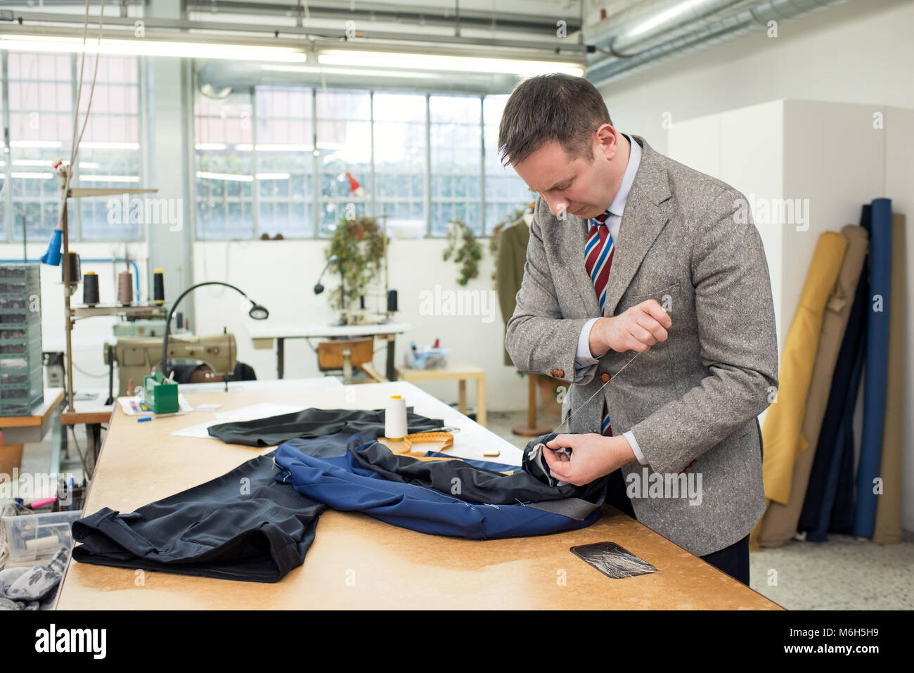 Sastre coser a mano el forro interior sobre una chaqueta sentado en una  mesa de trabajo en su taller Fotografía de stock - Alamy
