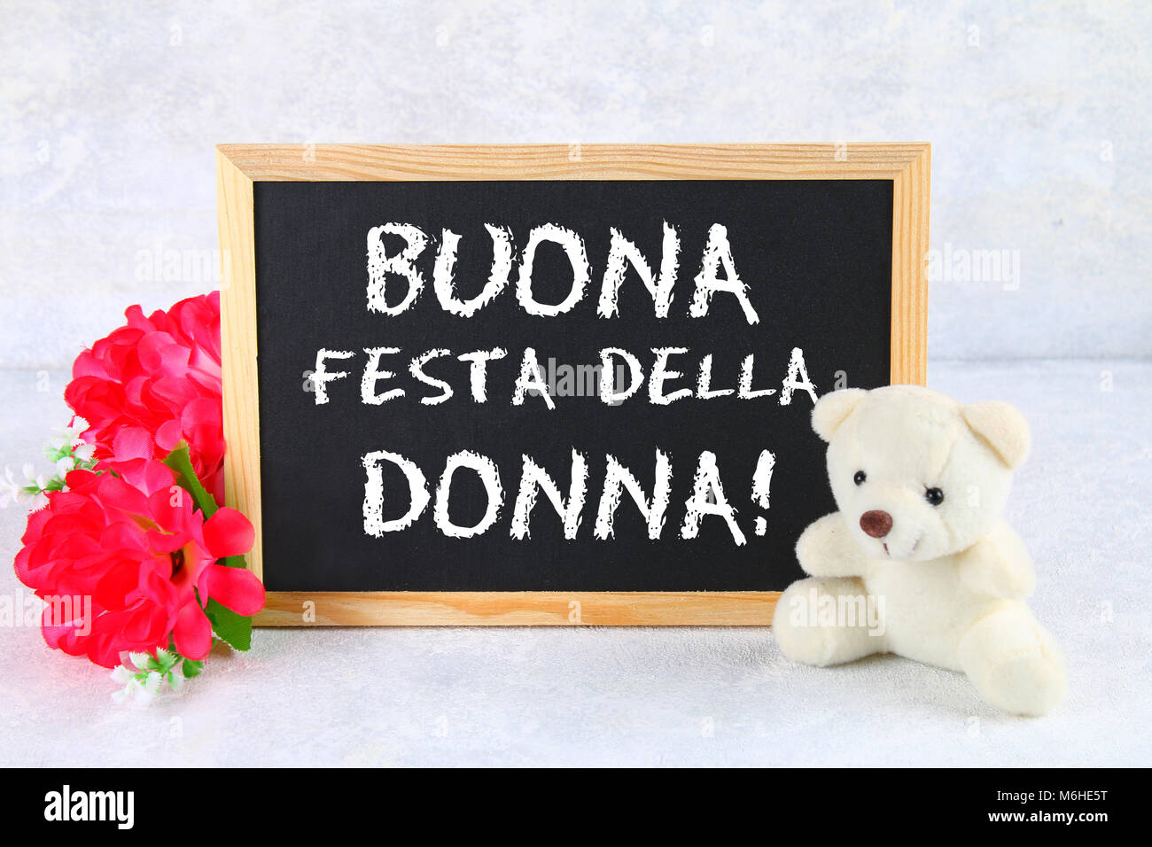 La inscripción en la pizarra en italiano: Feliz día de la mujer. Flores  rosas y oso de peluche Fotografía de stock - Alamy