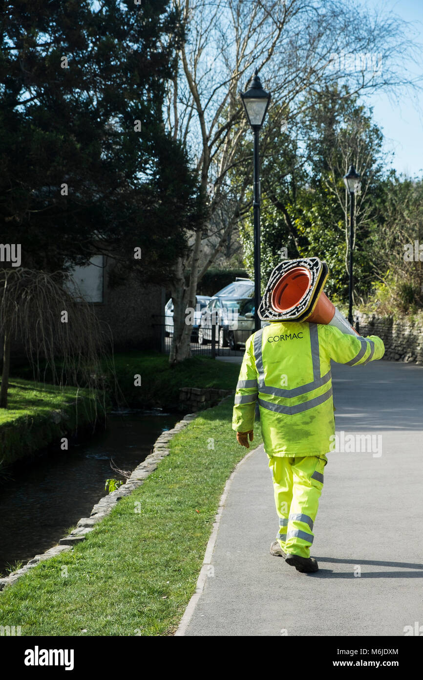 Un trabajador Cormac llevar conos de tráfico en jardines Trenance Newquay Cornwall. Foto de stock