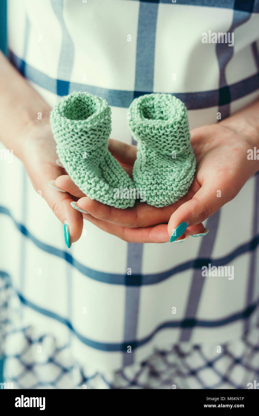 La hembra manos sujetan el tejido verde pequeña zapatos para bebé recién nacido. Toma de primer plano. Sin rostro Fotografía stock - Alamy