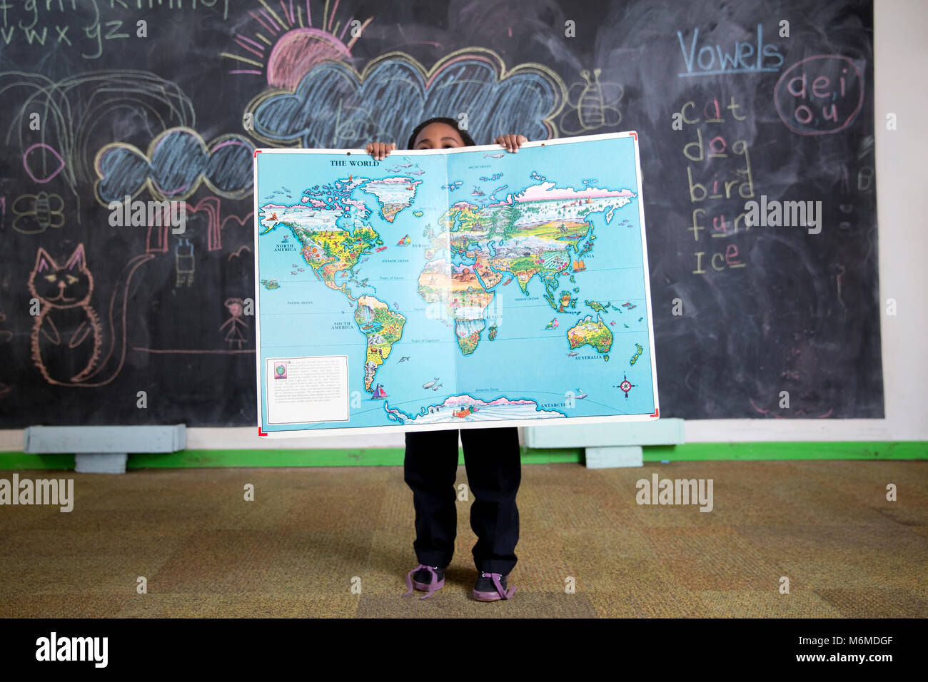 Niña de la escuela mantiene un mapa del mundo Foto de stock