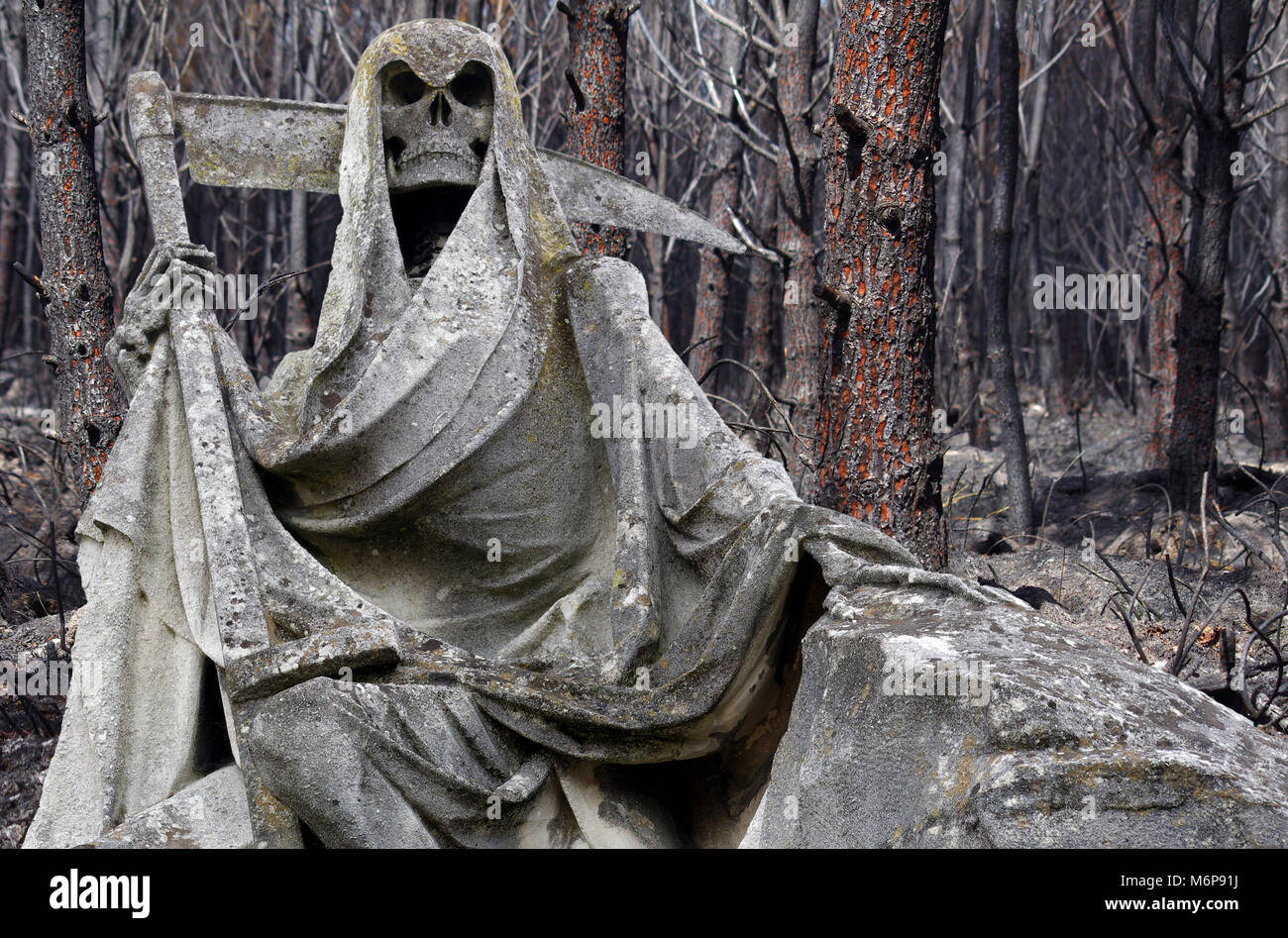 Guadaña estatua con bosques destruidos por el fuego en segundo plano. Foto de stock