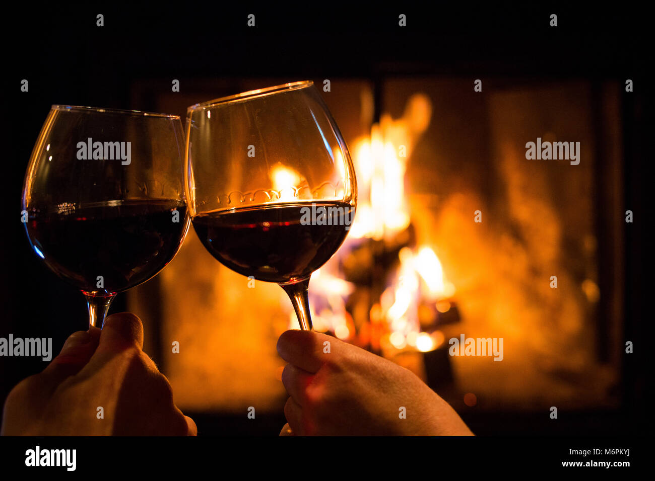 Par la celebración de gafas con vino al pozo de fuego cerrar Foto de stock