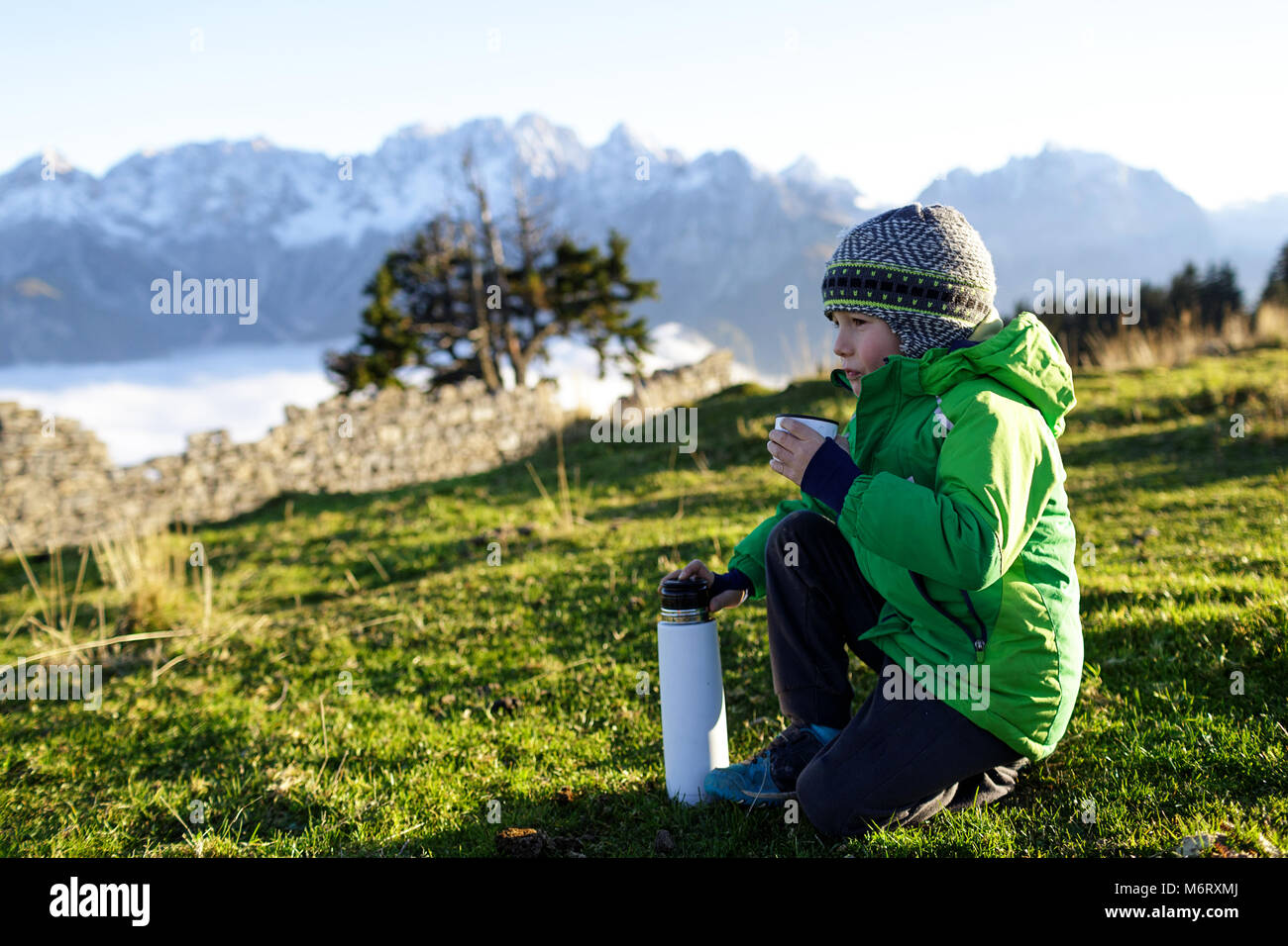 Joven calentando por beber bebida caliente de los termos fuera en las  montañas, con ropa de invierno en Fotografía de stock - Alamy