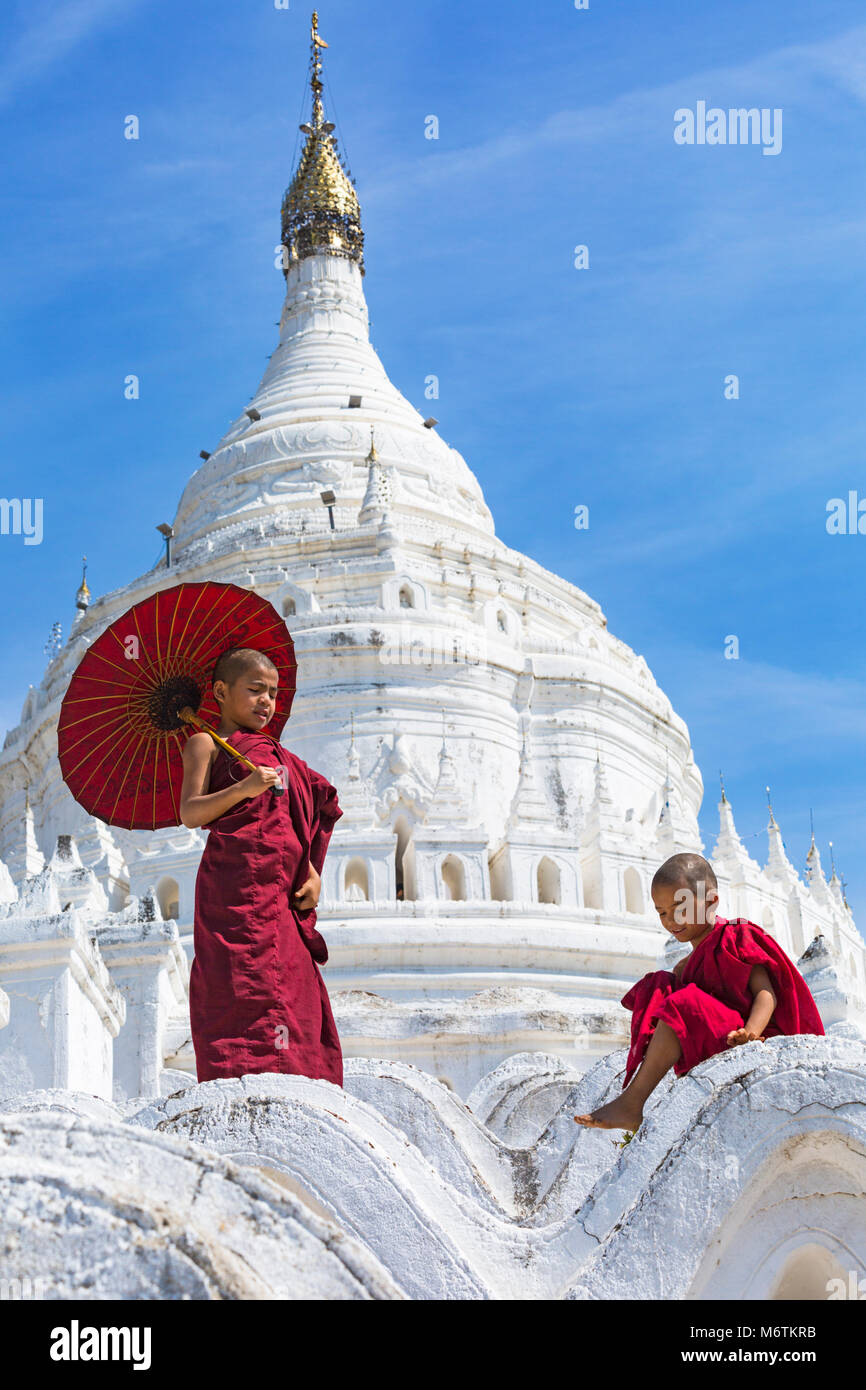 Joven novicio monjes budistas, uno sosteniendo una sombrilla y uno sentado en la Pagoda Myatheindan (también conocida como la Pagoda de Hsinbyume), Mingun, Myanmar (Birmania) Asia Foto de stock