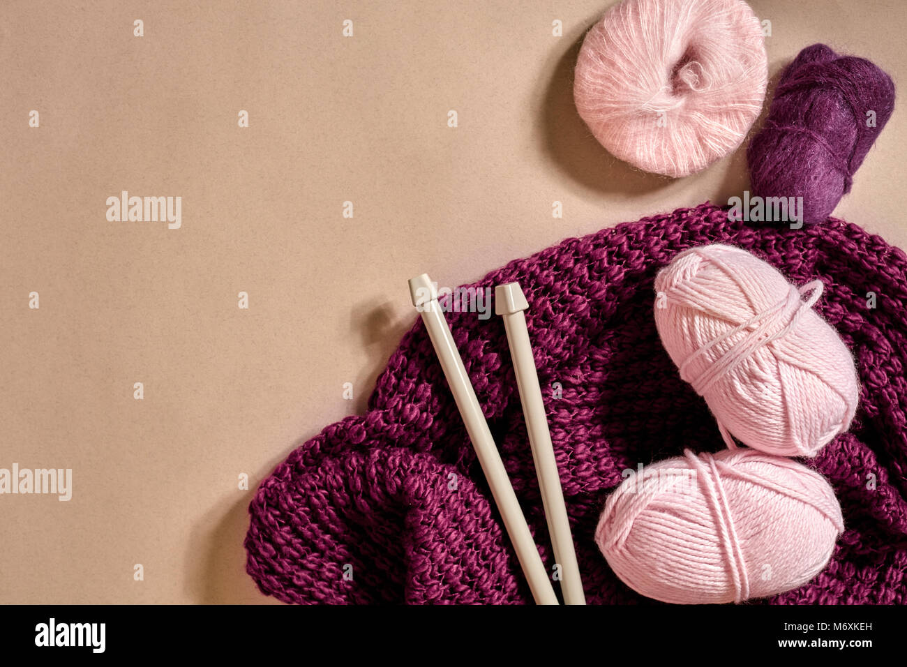 Tres rosas bolas de hilo de tejer, agujas de tejer y púrpura plaid tejidos  vista superior Fotografía de stock - Alamy