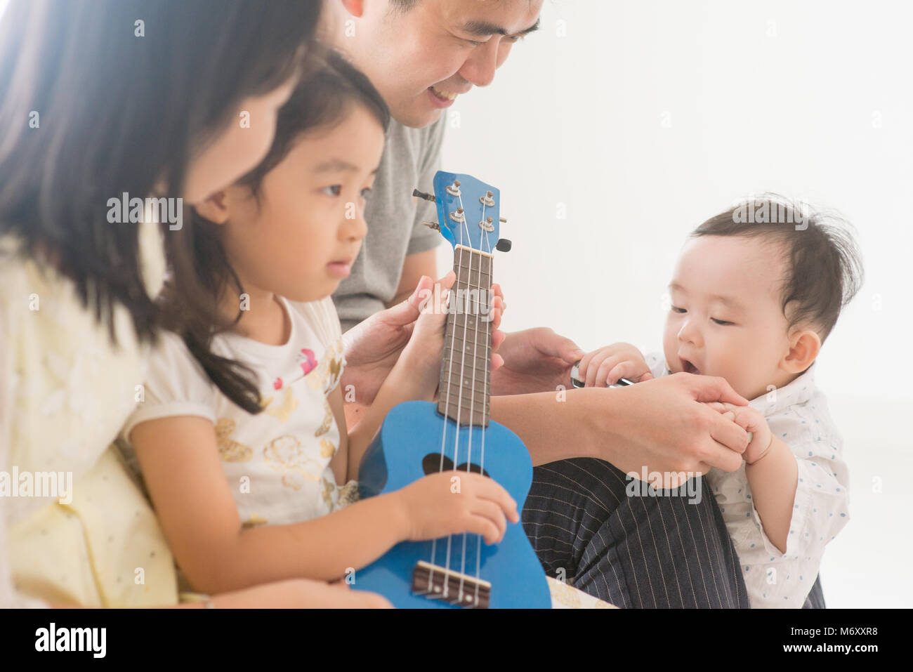 Padres y niños jugando ukulele juntos. Familia de Asia pasar tiempo de  calidad en casa, estilo de vida natural en el interior Fotografía de stock  - Alamy