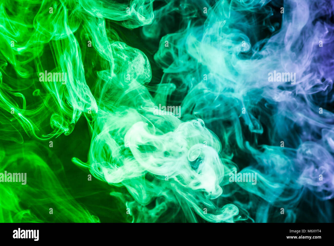Humo de colores verde y azul sobre un fondo negro aislado. Antecedentes  Desde el humo de vape Fotografía de stock - Alamy
