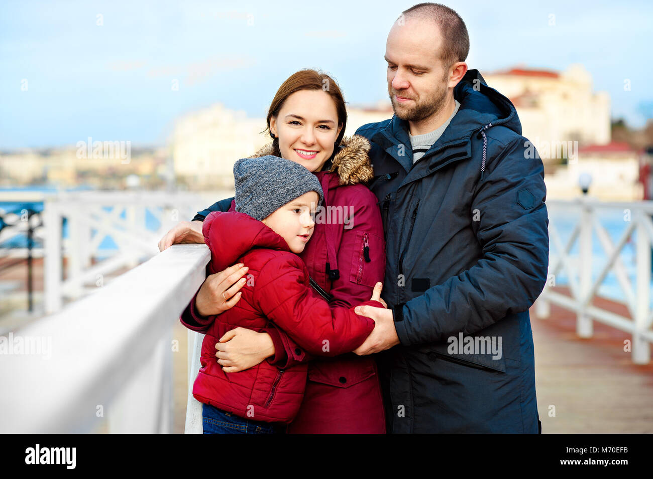 Familia feliz con el hijo de pie al borde del mar en primavera Foto de stock