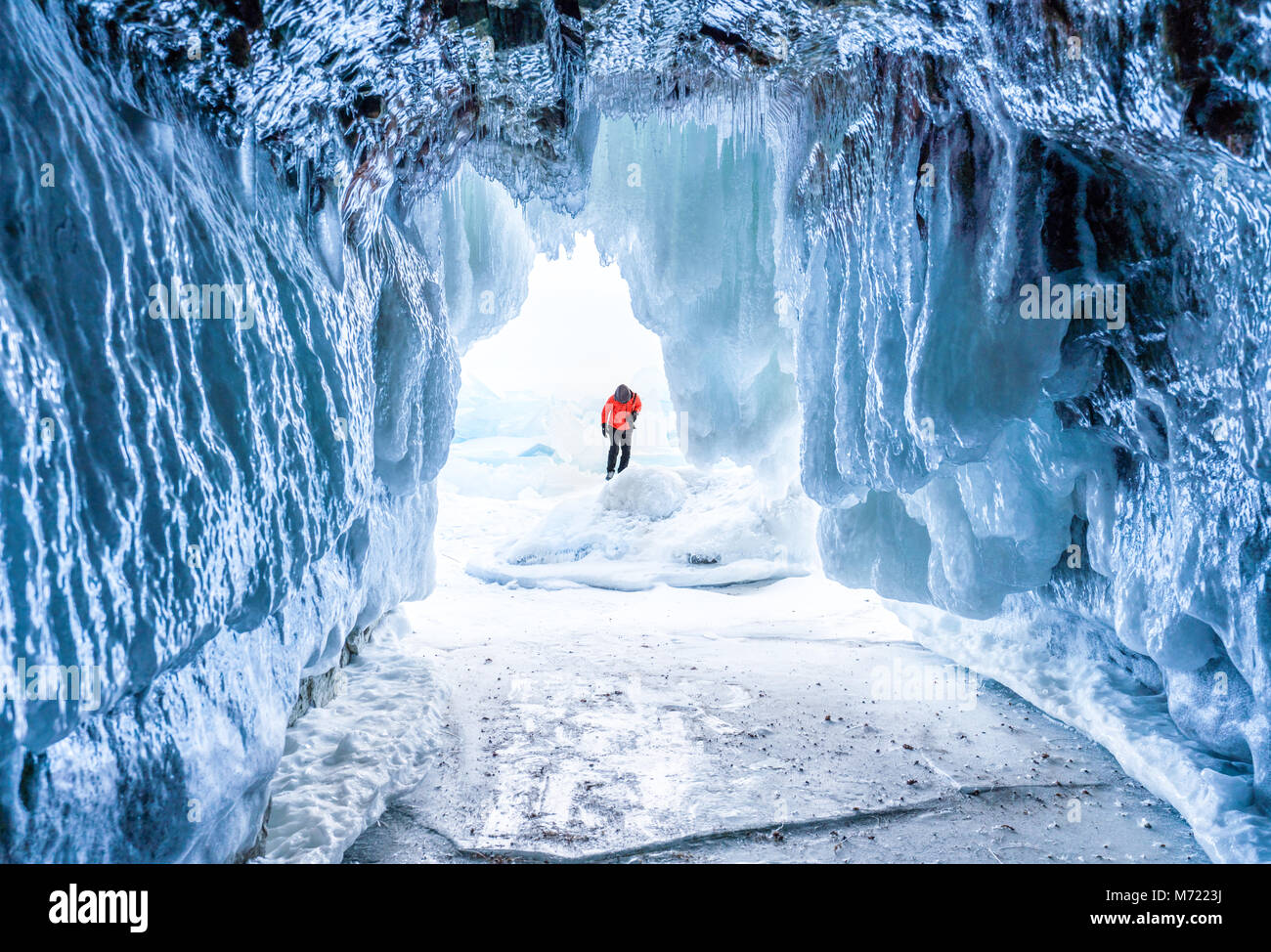 Paisaje invernal, cueva de hielo congelado con el joven fotógrafo de pie solo. Viajar en invierno Foto de stock
