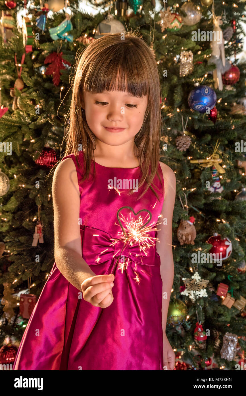 Cinco años de edad, niña sosteniendo una bengala en forma de corazón en Navidad Foto de stock