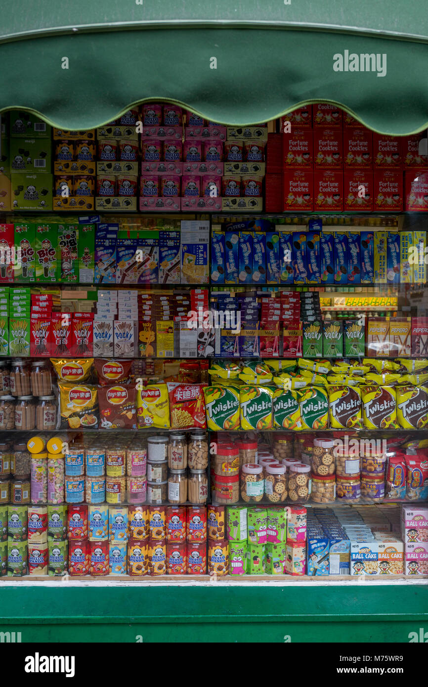 Un detalle de un surtido de aperitivos, como galletas, papas fritas y otras mercancías en los estantes de una tienda de la esquina (tienda de conveniencia) ventana en Gerrard Street, Chinatown, el 5 de marzo de 2018, en Londres, Inglaterra. Foto de stock