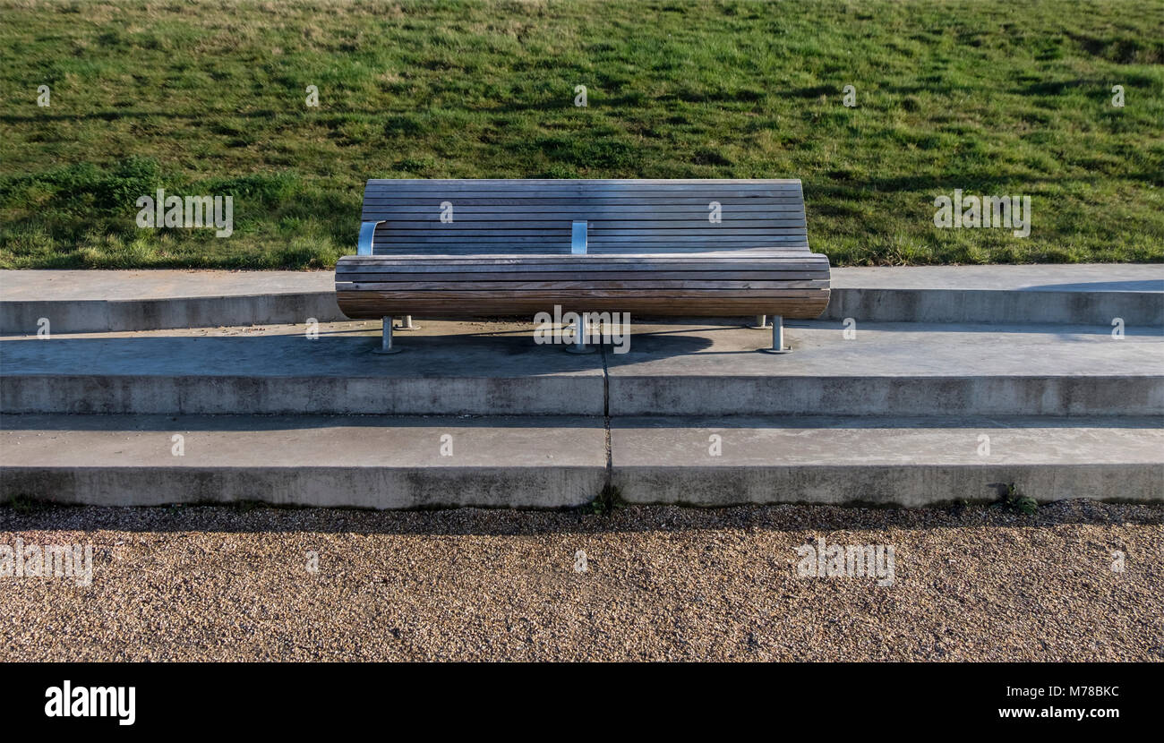 Banqueta moderna en el parque con espacio, cerca de la hierba y la ruta de fondo, sentirse tranquilo, solitario y calma Foto de stock