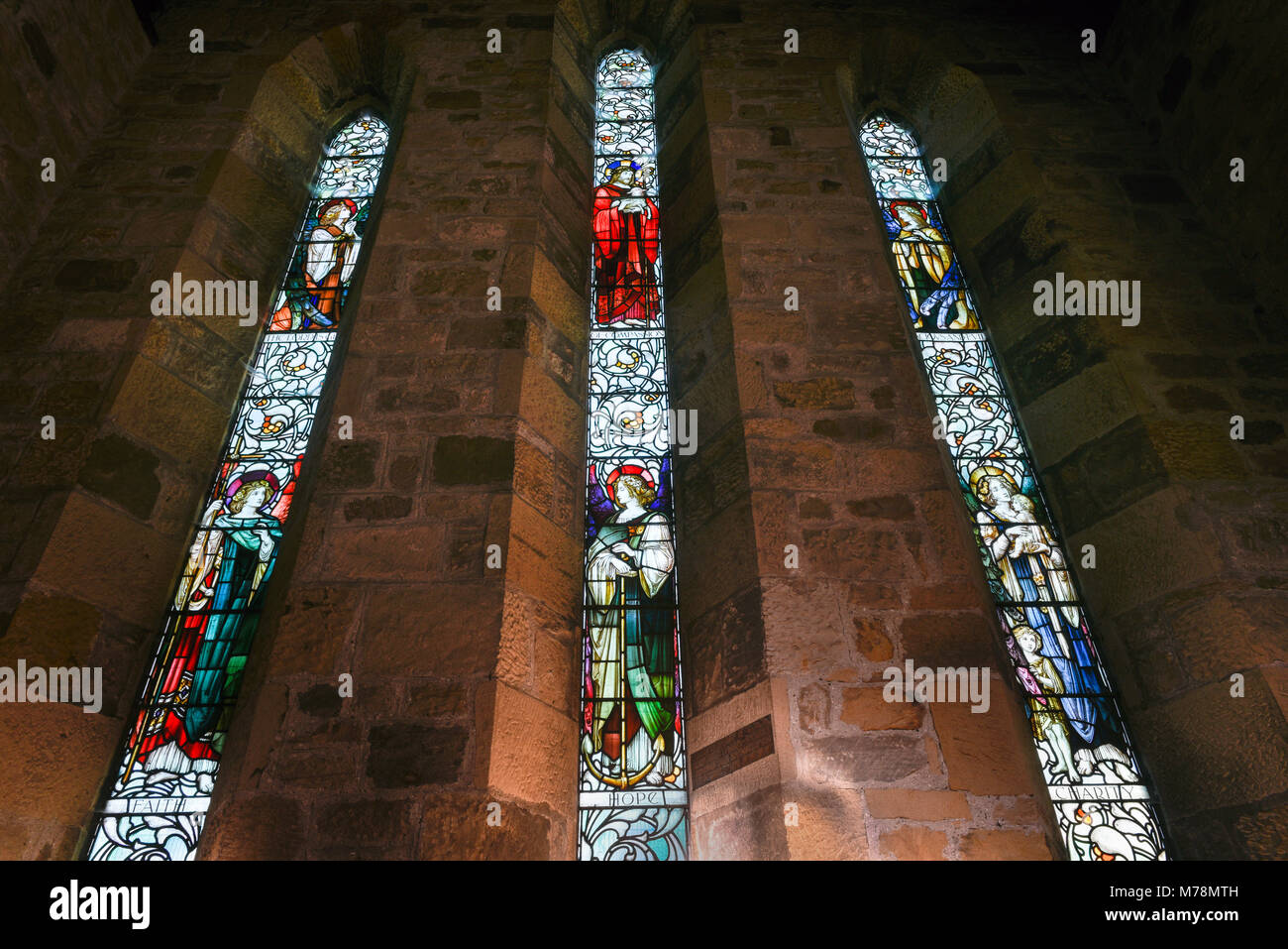 Vista interior mirando hacia la fe, la esperanza y la caridad, las vidrieras de la iglesia parroquial de San Andrés, Corbridge Foto de stock