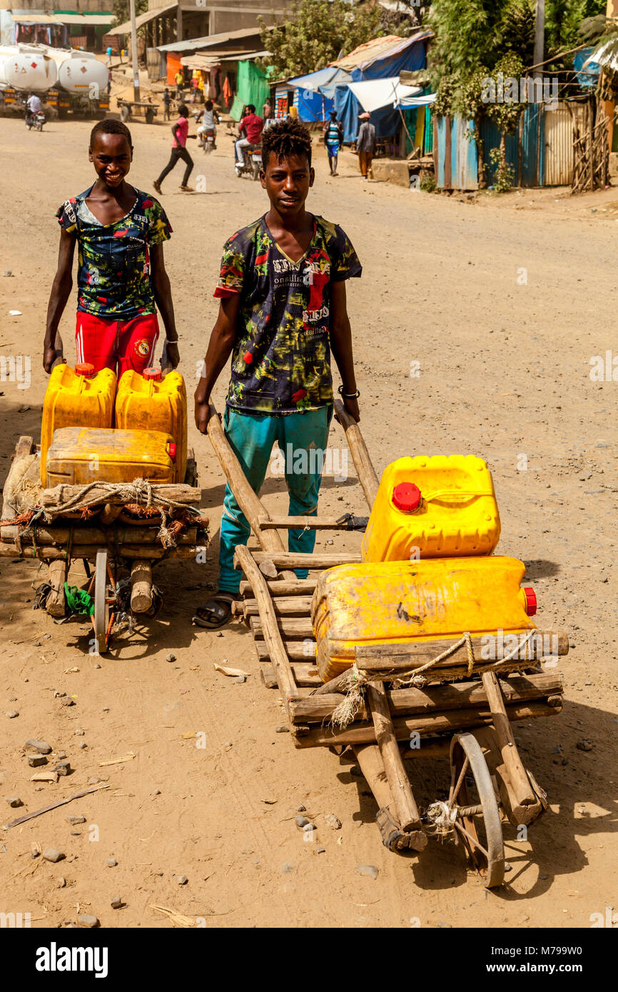 Los chicos locales de transporte de agua en la ciudad de Jinka