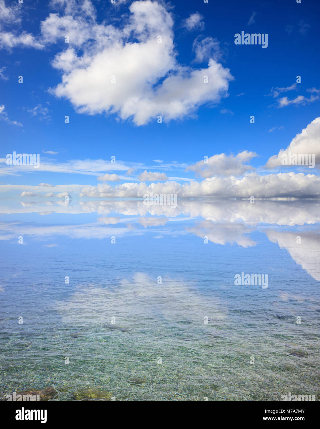 Claro transparente en la superficie del mar. En aguas poco profundas, cielo azul con nubes antecedentes Foto de stock