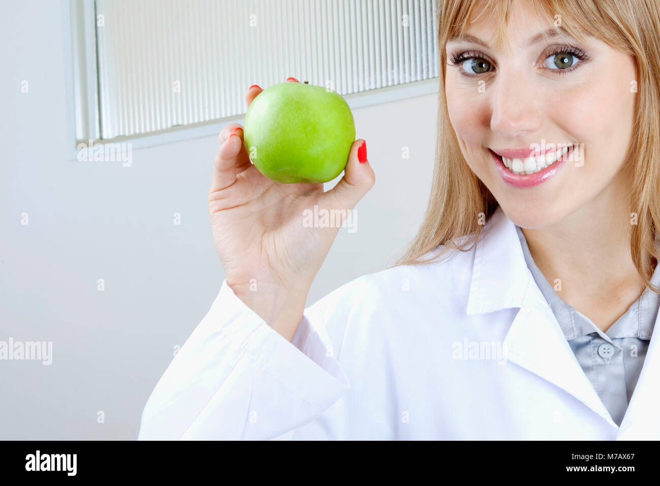 Dentista Femenino Mostrando Una Manzana Granny Smith Y Sonriente