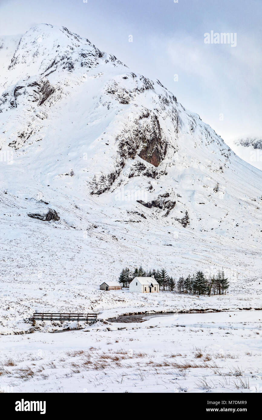 Una casita blanca en las montañas con nieve en invierno Foto de stock