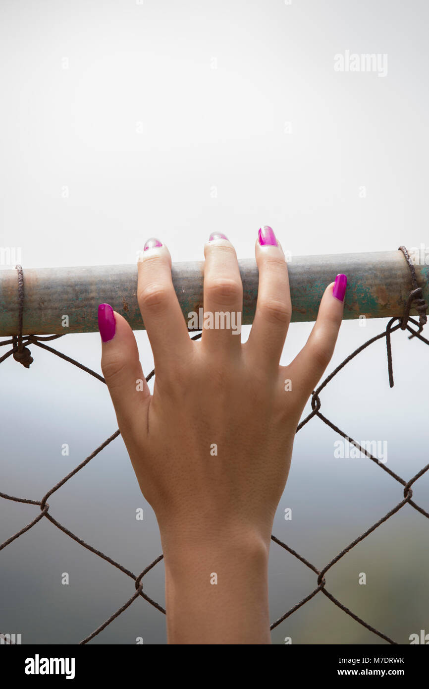 Cerca de una mujer de la mano sobre la valla metálica Foto de stock