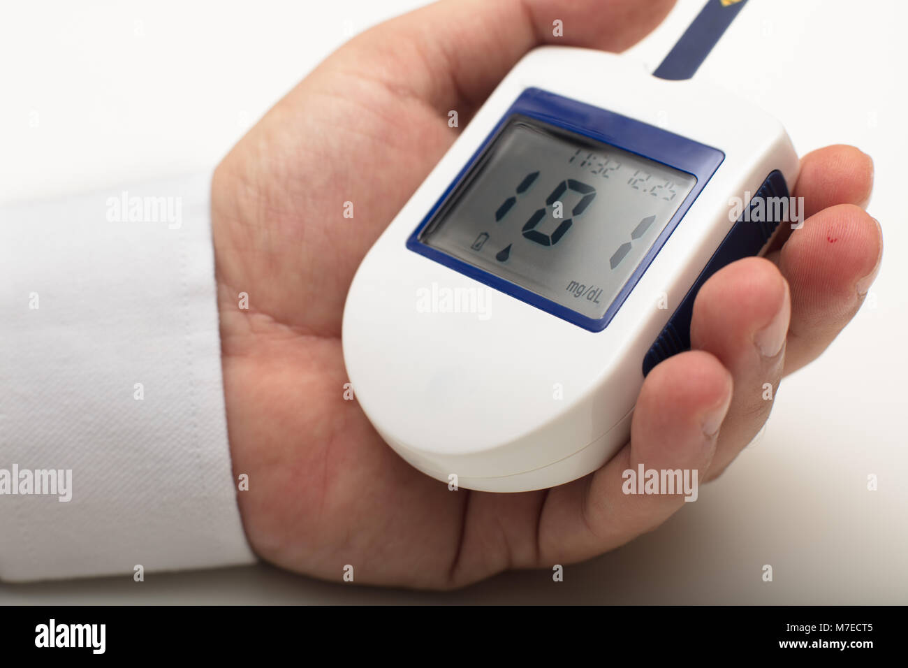 Mano que sostiene un medidor de glucosa de sangre que mide el azúcar de  sangre, el fondo es un estetoscopio y un archivo de carta