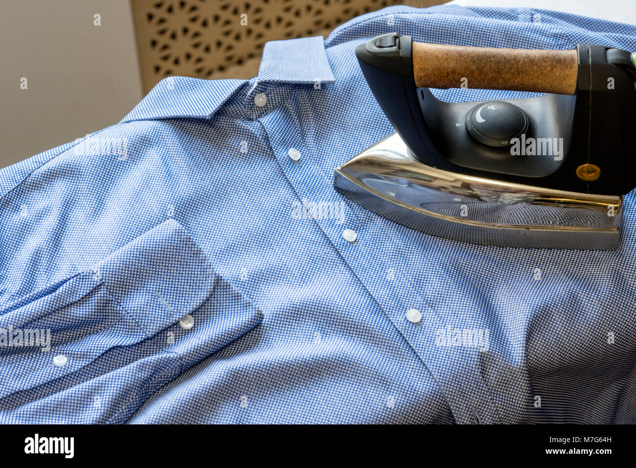 Los trazos de hierro el hombre de la camisa azul. Limpieza y pulcritud Foto de stock