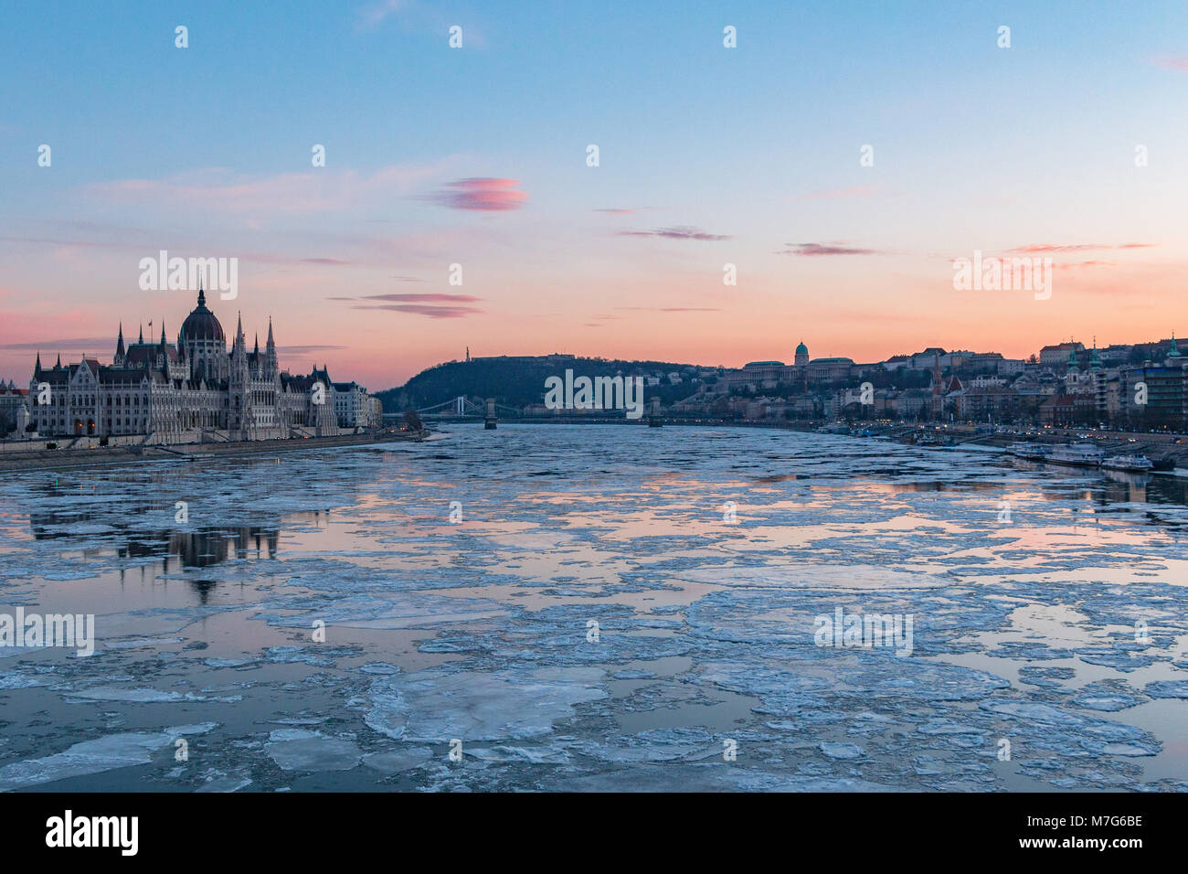 El edificio del Parlamento húngaro y el Palacio Real con témpanos de hielo sobre el Danubio en Budapest en invierno Foto de stock